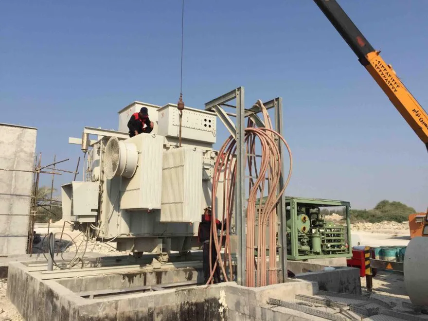 Crane lifting a power transformer during on-site installation